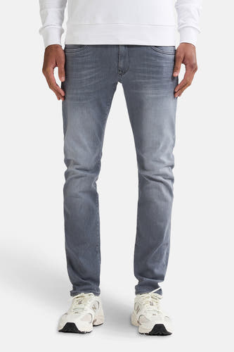 Jean slim en denim gris de Petrol Industries, avec un lavage subtil et porté avec des baskets blanches et un sweat-shirt blanc.