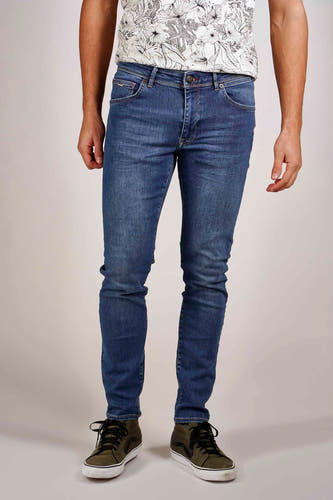 Jean slim en denim par Petrol Industries®, avec des poches arrière et des baskets hautes vertes.