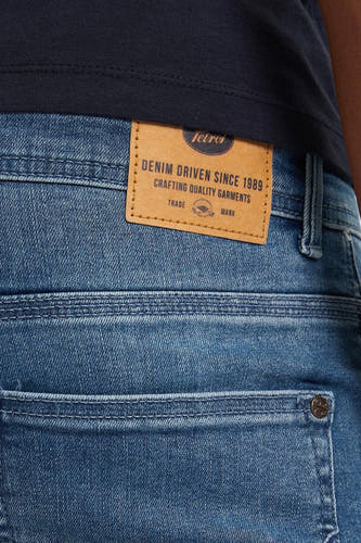 Lichtblauwe slim fit jeans van Petrol Industries, met een leren merklabel op de achterkant en een subtiele textuur.
