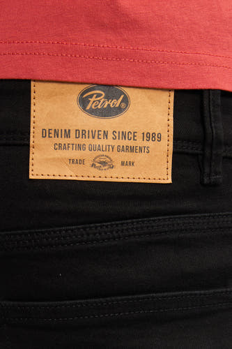 Jean slim fit noir de Petrol Industries avec un étiquette en cuir brun sur le dos.