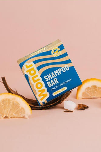 Gel douche multicolore en barre de WONDR CARE, sur une échelle de noix de coco entre des morceaux de citron.