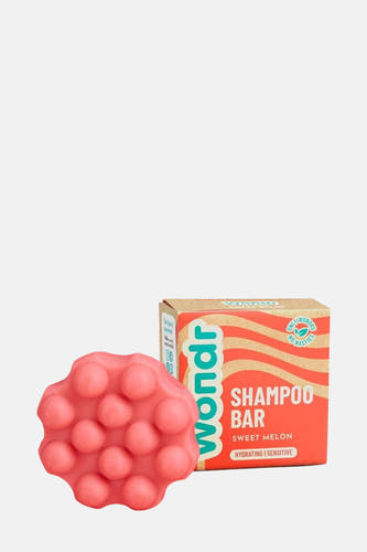 Roze shampoo bar van WONDR CARE, naast een kartonnen verpakking met golvend patroon.
