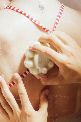 Produit de soin multicolore de WONDR CARE, utilisé pendant le lavage avec un maillot de bain rayé rouge et blanc.
