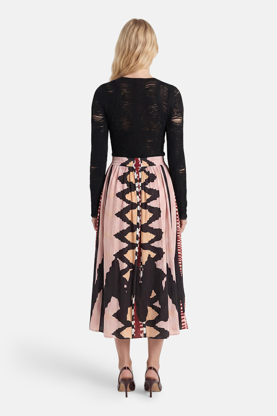 Multicolor lange rok met geometrisch patroon van ADORE, getoond van achteren met zwarte mesh top en bruine hakken