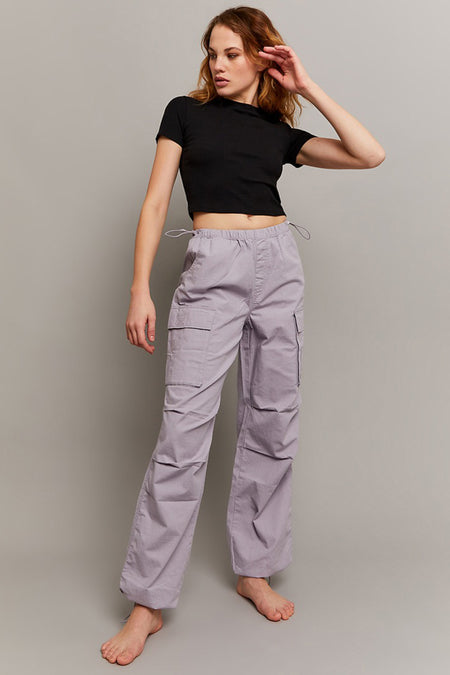 Jean cargo gris de TALLY WEIJL, avec poches et cordon, porté avec un t-shirt noir et des pieds nus.