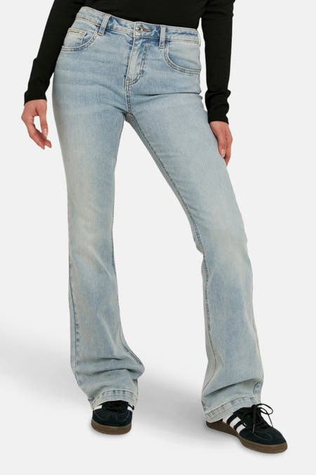 Jean bootcut en denim bleu de TALLY WEIJL, associé à une chemise noire et des baskets rayées.