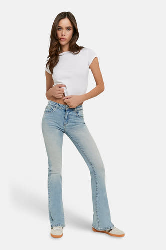 Jean flare bleu clair de TALLY WEIJL, avec un design à cinq poches et porté avec un t-shirt blanc et des baskets.