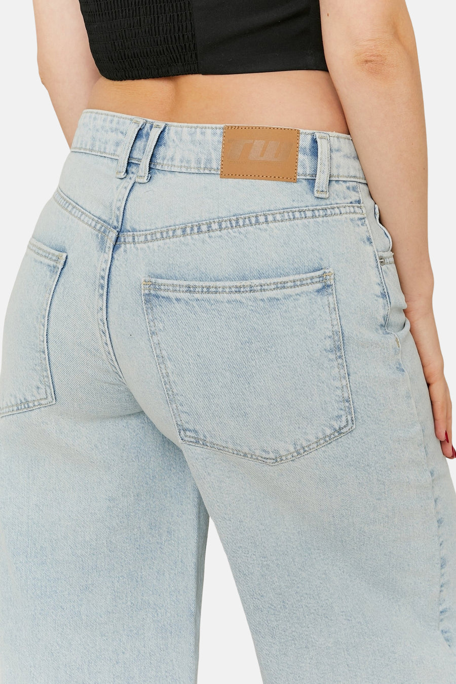 Close-up van de achterkant van een vrouw in lichtblauwe spijkerbroek.