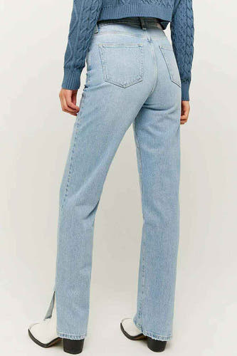 Jean droit bleu clair de TALLY WEIJL, avec des fentes en bas, combiné avec un pull bleu et des bottines blanches.