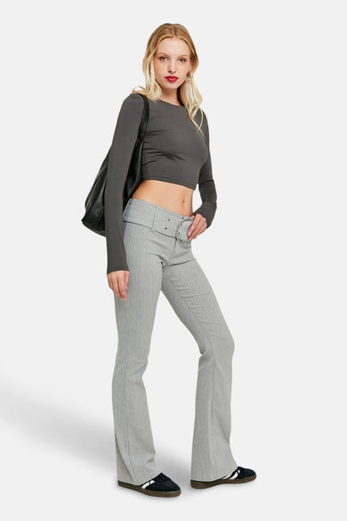 Pantalon gris de TALLY WEIJL, avec une rayure blanche et une ceinture, porté avec un haut court gris et un sac noir.