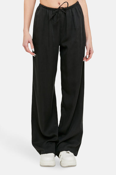 Pantalon noir de TALLY WEIJL, avec cordon et jambes larges, associé à des sneakers blanches.