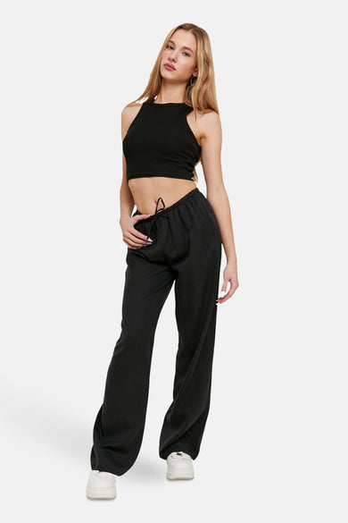 Pantalon noir de TALLY WEIJL, avec des jambes larges et une ceinture élastique, associé à un haut noir et des baskets blanches.