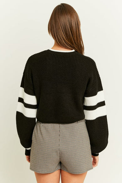 Sweat-shirt noir à col rond de TALLY WEIJL, avec des rayures blanches sur les manches, porté avec un short à carreaux.