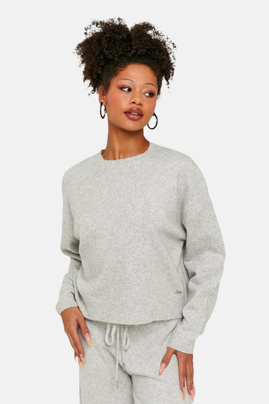 Sweat-shirt gris à col rond de TALLY WEIJL, avec des manches longues, porté avec un short de jogging coordonné.