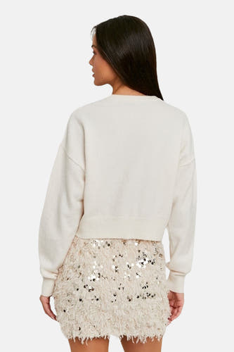 Pull blanc avec col rond de TALLY WEIJL, à longues manches, associé à une jupe pailletée.