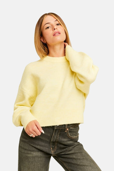 Pull jaune à col rond de TALLY WEIJL, tricoté en douceur avec des manches volumineuses remarquables et des bords-côtes, porté avec un jean foncé.