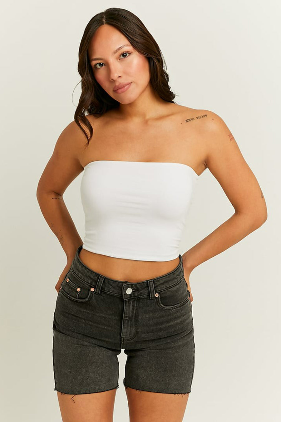 Vrouw met wit topje en zwarte denim shorts.
