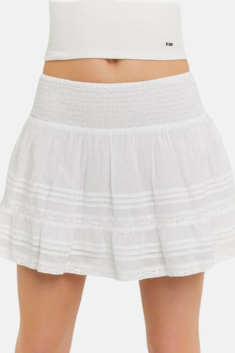 Jupe blanche TALLY WEIJL avec taille smockée, volants superposés et détails en dentelle, portée avec un crop top blanc.