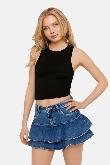 Jupe en jean bleu moyen de TALLY WEIJL, une jupe courte et superposée portée par un mannequin avec un crop top noir.