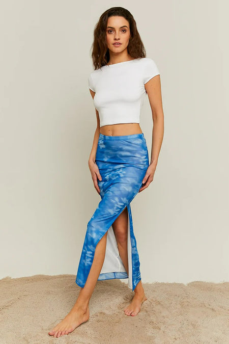 Longue robe bleue de TALLY WEIJL, avec encolure dégagée et imprimé nuageux, associée à un crop top blanc.
