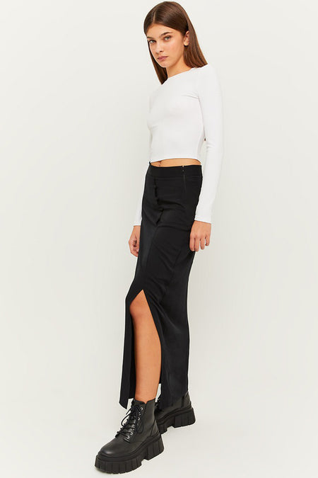 Jupe longue noire fendue sur le côté de TALLY WEIJL, portée avec un crop top blanc et des bottes noires, vue de profil