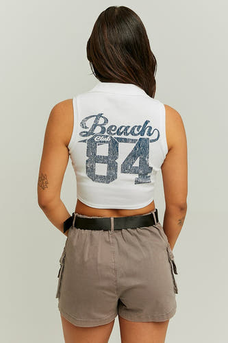 T-shirt sans manches de TALLY WEIJL, imprimé 'Beach Club 84' sur le dos, associé à des shorts gris et une ceinture noire.