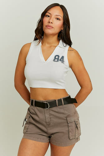 T-shirt sans manches blanc de TALLY WEIJL, avec une application '84' et porté avec des shorts cargo bruns et une ceinture noire.