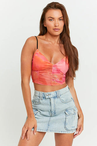 Vrouw met roze top en denim rok.