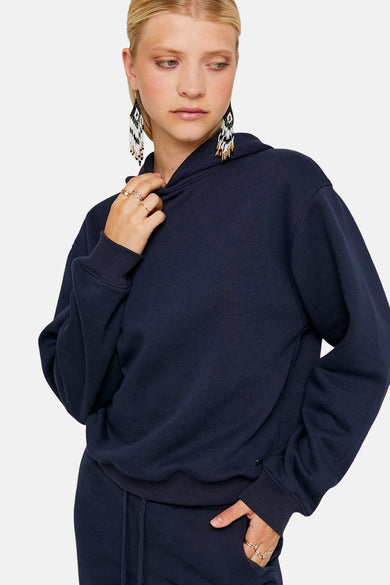 Pull-over bleu avec capuche de TALLY WEIJL, porté avec des bijoux et un pantalon coordonné.