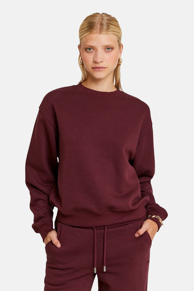 Gilet de Bordeaux de TALLY WEIJL, porté par un mannequin avec des boucles d'oreilles et un bracelet en or, associé à un pantalon de jogging.