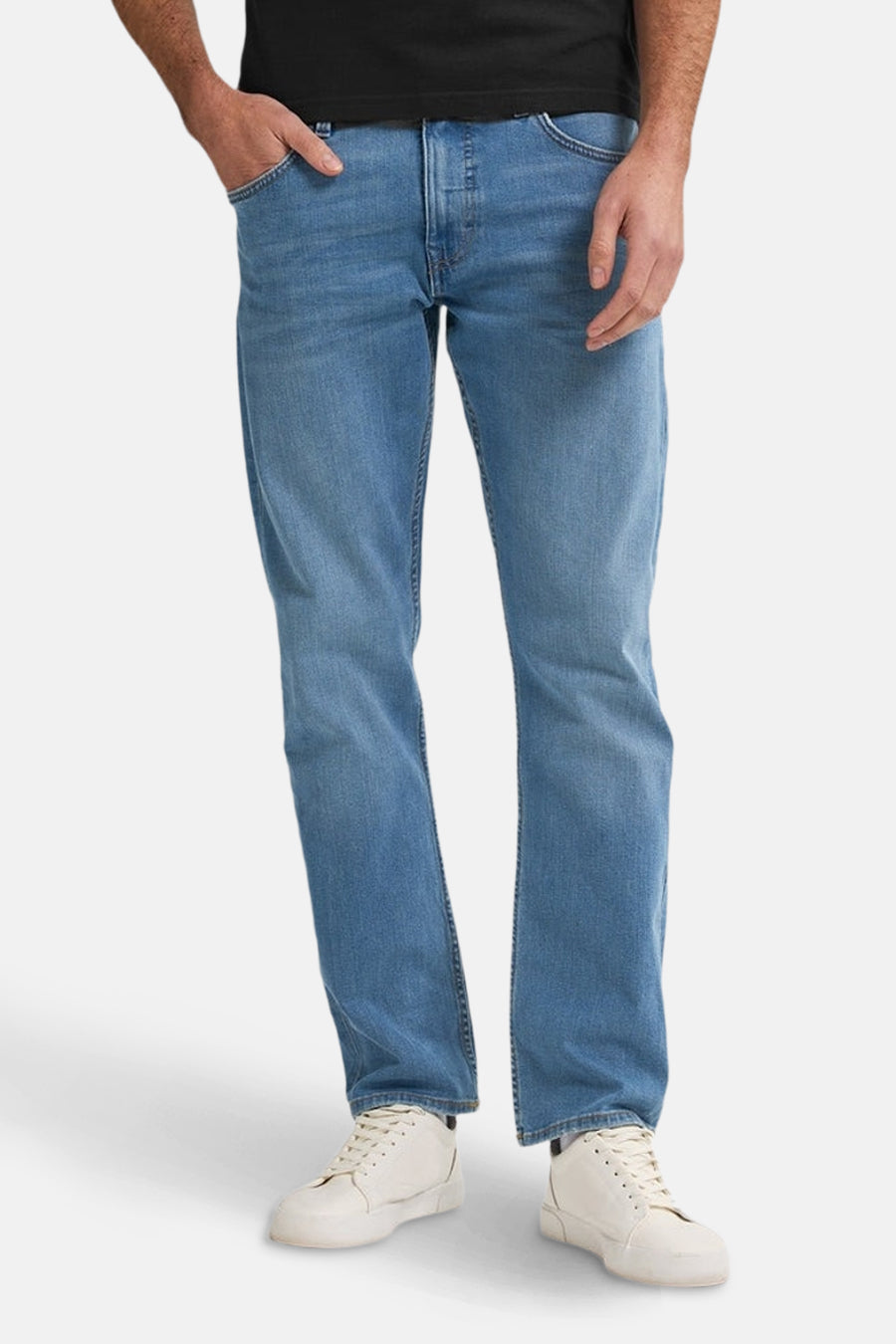 Een man draagt blauwe jeans en witte sneakers.