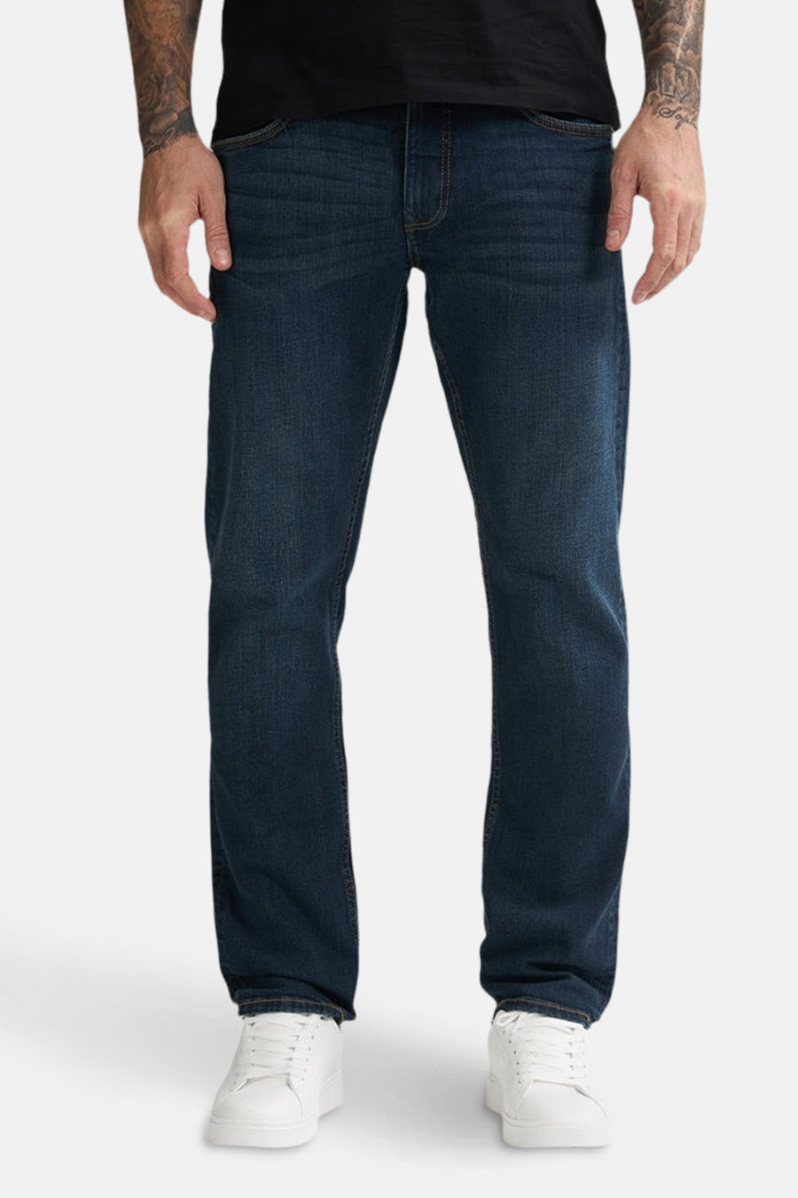 Een man met blauwe jeans en witte sneakers.