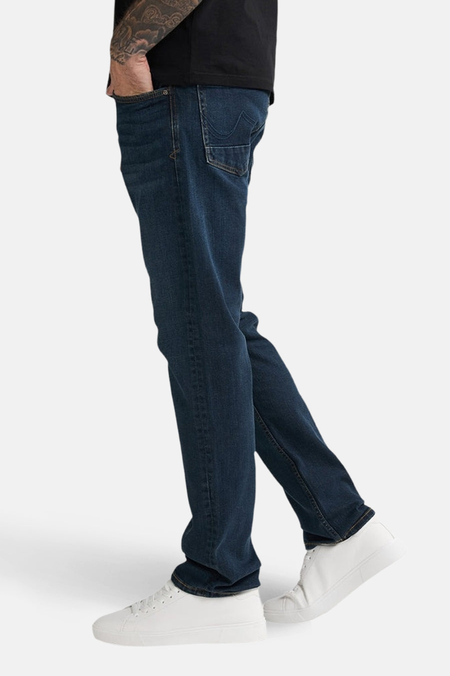 Persoon in blauwe jeans en witte sneakers.
