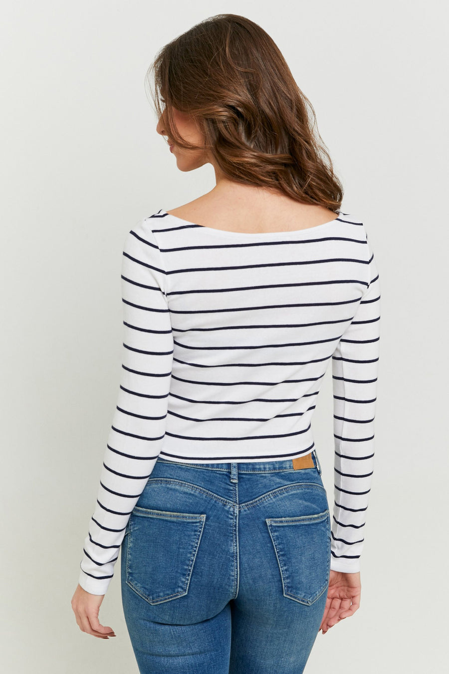 T-shirt blanc à manches longues rayé de TALLY WEIJL, avec une encolure bateau, combiné avec un jean bleu.