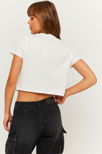 T-shirt blanc de TALLY WEIJL, à manches courtes, modèle crop top, associé à un pantalon noir.