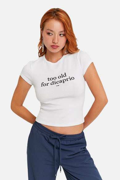 T-shirt blanc à manches courtes de TALLY WEIJL, avec le texte "trop vieux pour DiCaprio", associé à un short de jogging bleu.