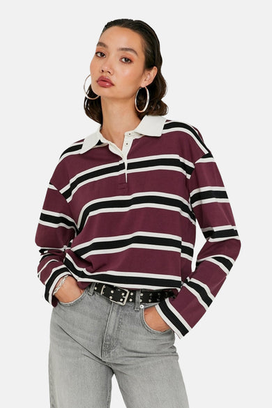 Polo de Bordeaux à longues manches de TALLY WEIJL, avec des rayures noires et blanches et un col blanc, associé à des jeans gris et une ceinture noire.