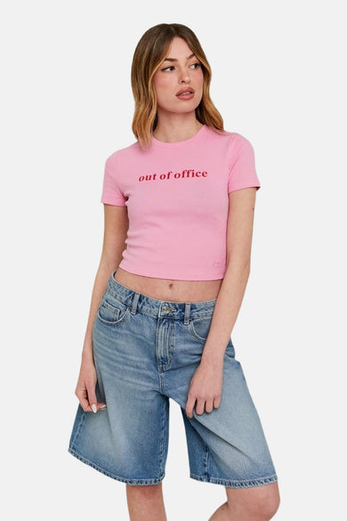 T-shirt rose à manches courtes de TALLY WEIJL, avec du texte rouge "out of office", porté avec des shorts de jeans larges.