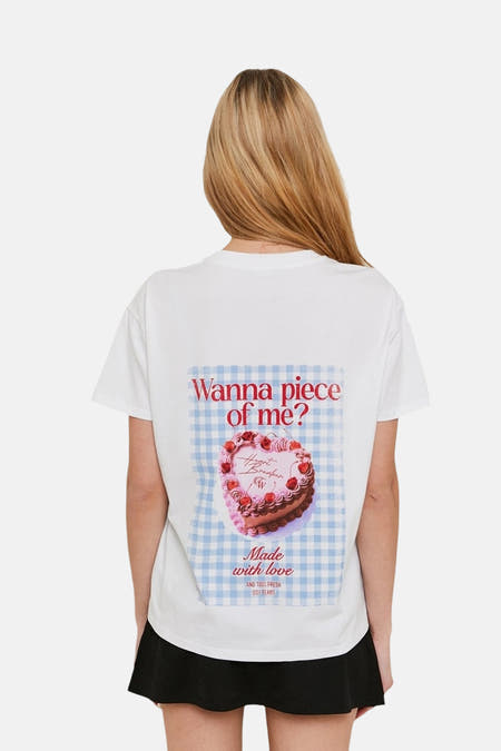 T-shirt blanc à manches courtes de TALLY WEIJL, avec un imprimé d'une tarte sur le dos, porté avec une jupe noire.