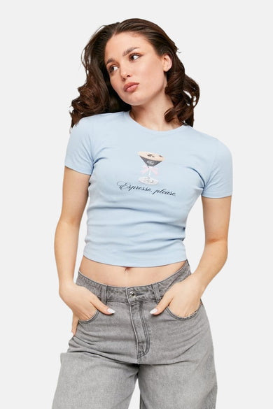T-shirt bleu à manches courtes de TALLY WEIJL, avec imprimé espresso martini sur le devant, associé à des jeans gris.