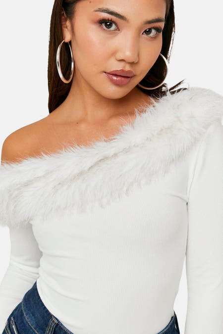 T-shirt écru à manches longues de TALLY WEIJL, avec un col en fausse fourrure blanche et de grandes boucles d'oreilles argentées.