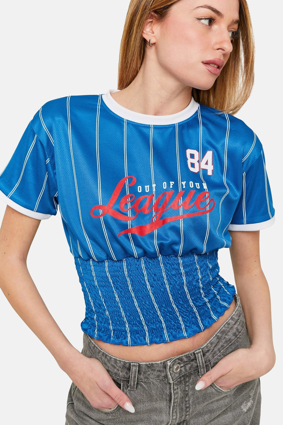 Vrouw in blauwe gestreepte crop top en grijze jeans.