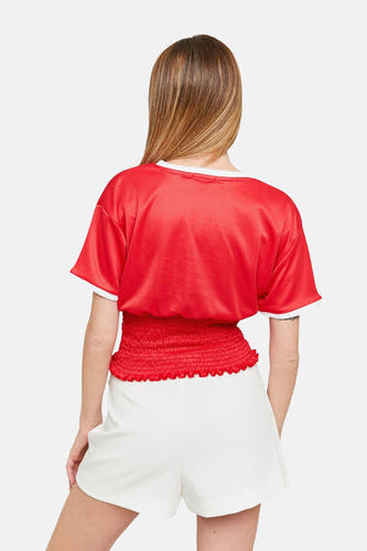 T-shirt rouge à manches courtes de TALLY WEIJL, avec une ceinture plissée, porté avec un short blanc.