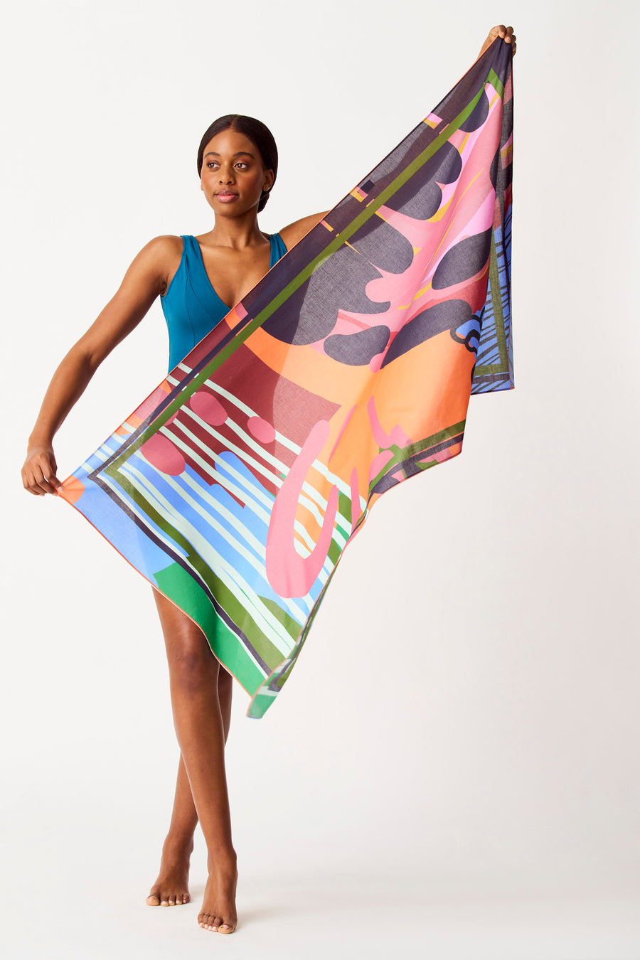 Lingue multicolore de SUNSET STUDIO, avec un motif géométrique frappant, tenue par une femme en un maillot de bain bleu.