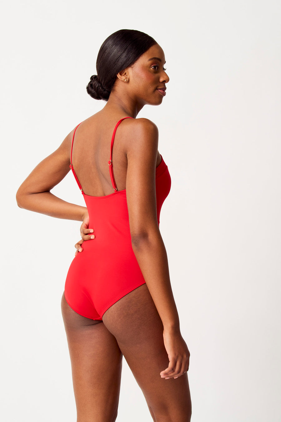 Rood badpak van SUNSET STUDIO, gezien van opzij op een model met een opgestoken kapsel.
