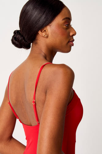 Sac de sport rouge SUNSET STUDIO, vu de côté avec des bandes fines et des détails dorés.