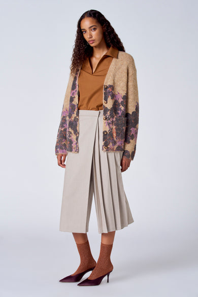 Pull marron avec col V de SUNSET STUDIO, associé à un gilet tricoté, des culottes beige et des chaussettes marron scintillantes avec des talons.