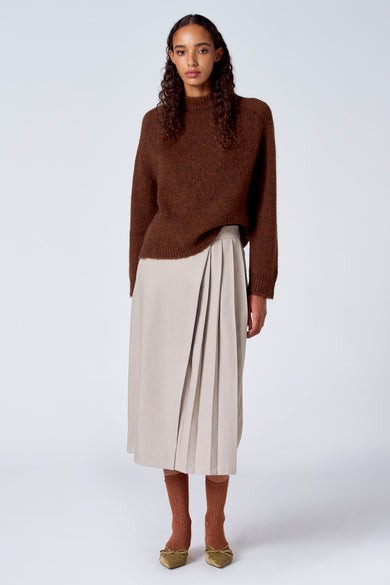 Pull marron avec col rond de SUNSET STUDIO, associé à une jupe midi beige et des chaussettes marrons avec des chaussures olive.