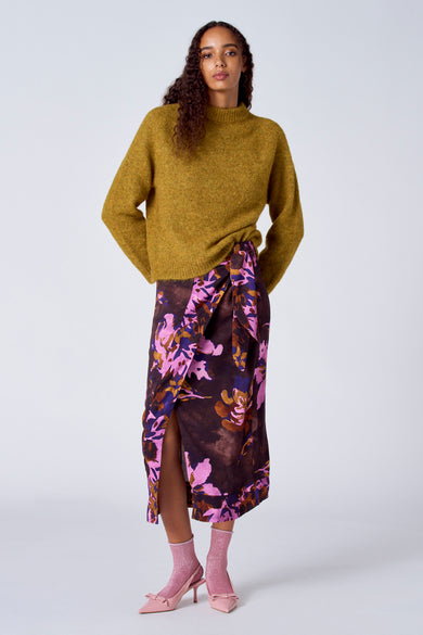 T-shirt jaune avec col rond de SUNSET STUDIO, porté avec une robe à fleurs et des chaussures roses.
