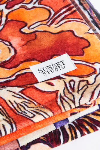 Maillots de bain orange SUNSET STUDIO avec un motif abstrait de fleurs et une étiquette de marque visible.